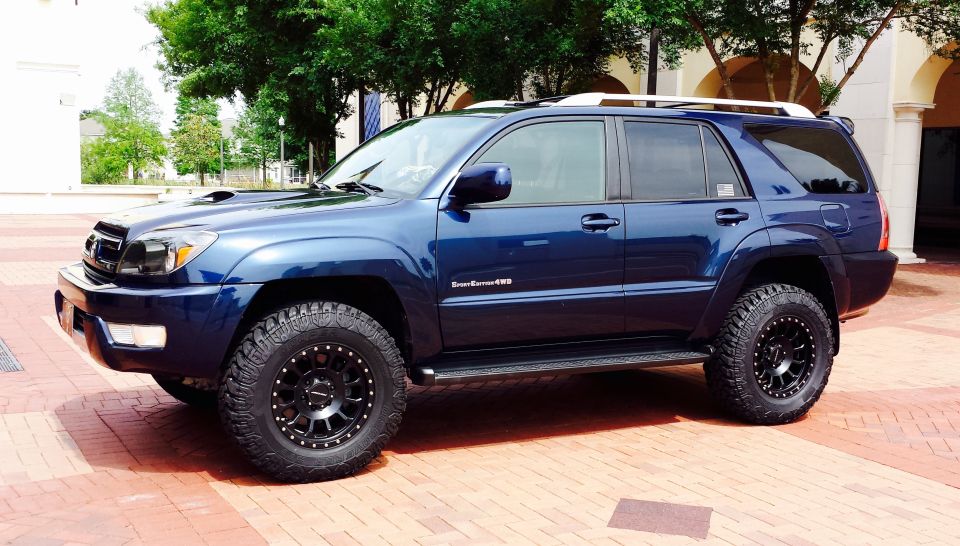 Blue 2005 Toyota 4Runner with aftermarket wheels and tires parked on brick pavement