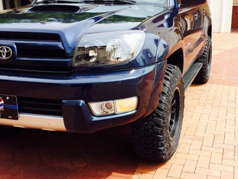 2005 Toyota 4Runner - The front quarter panel and headlight of a dark blue Toyota 4Runner are visible, showing off its tires.