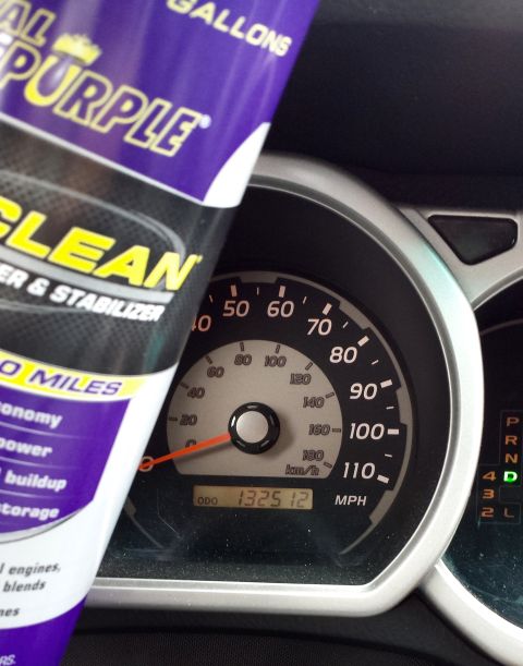 2005 Toyota 4Runner - A bottle of purple cleaner is held up in front of the dashboard gauges of a vehicle.
