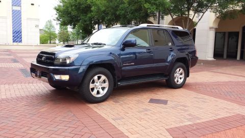 2005 Toyota 4Runner - Dark blue SUV with a hood scoop is parked on a brick-patterned surface.