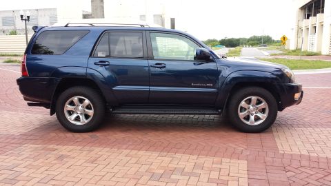 2005 Toyota 4Runner - Blue SUV parked on brick pavement, side view, showing "4Runner" and "4WD" badges.