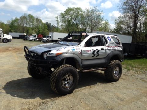 1999 Isuzu Vehicross - This heavily modified SUV features oversized tires and racing decals, suggesting it's built for off-road competition.