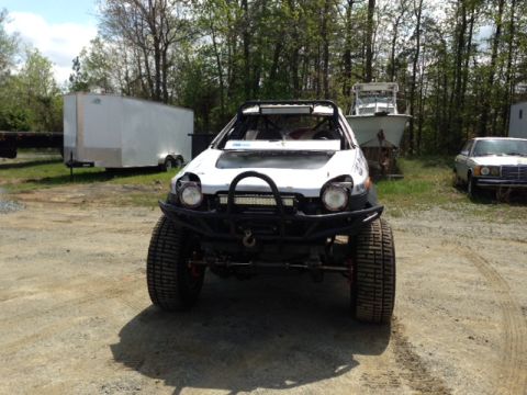 1999 Isuzu Vehicross - A heavily modified off-road vehicle sits in a lot with a trailer and another car in the background.
