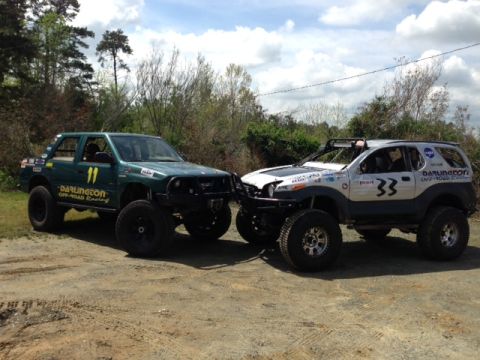 1999 Isuzu Vehicross - Two custom off-road SUVs, one green and one silver, are parked together outdoors.