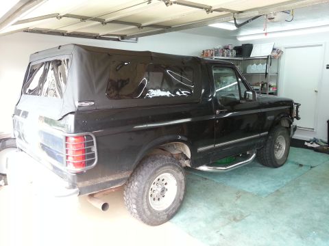 1994 Ford Bronco - This black Ford Bronco, likely a 1992 model, is parked inside a garage with its soft top on.
