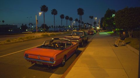 1995 Ford Taurus - Several cars are parked along a street at night, including a red convertible and a pickup truck.