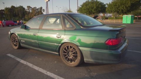 1995 Ford Taurus - 1995 Ford Taurus sedan parked in a lot, showing its rear quarter and aftermarket wheels.
