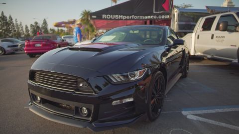 1995 Ford Taurus - A black Ford Mustang is parked in front of a ROUSH Performance tent at a car show.