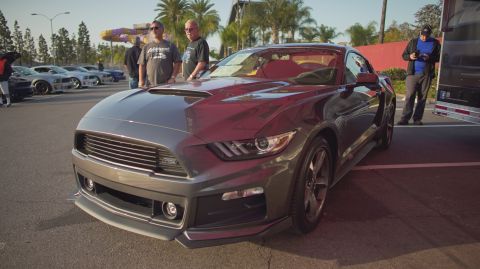 1995 Ford Taurus - A modern Ford Mustang is displayed at an outdoor car event with other vehicles in the background.