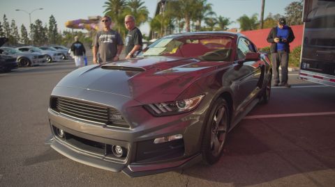 1995 Ford Taurus - A modern Ford Mustang is displayed at an outdoor car show with other vehicles in the background.