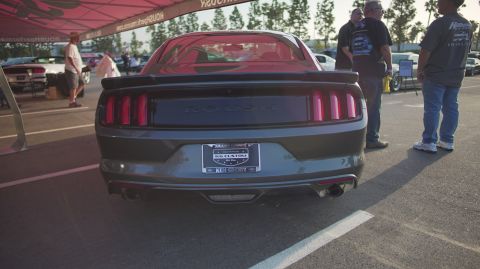 1995 Ford Taurus - Dark gray Ford Mustang with ROUSH badging and custom license plate frame at a car show.