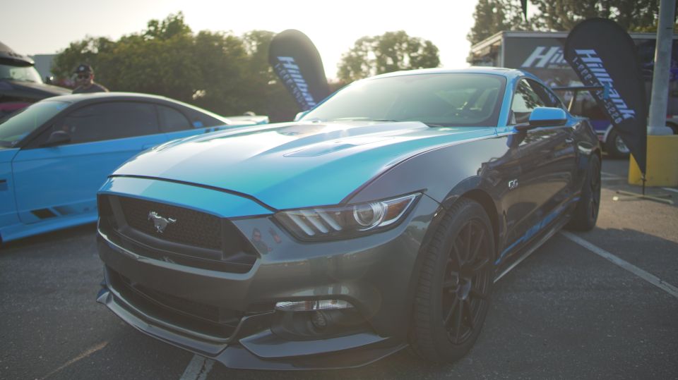 Front view of a gray and blue Ford Mustang GT with a blue Mustang in the background