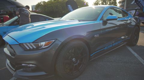 1995 Ford Taurus - A modified Ford Mustang with racing stripes and custom decals is parked at an outdoor event.