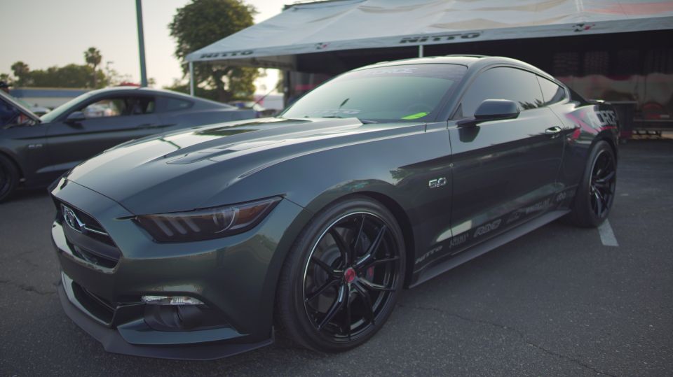 Dark green Ford Mustang coupe with black wheels and a '5.0' badge