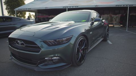 1995 Ford Taurus - A dark green Ford Mustang is parked in front of a tent, with another Mustang in the background.