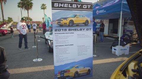 1995 Ford Taurus - A display board details the features of a 2015 Shelby GT at an outdoor car event.