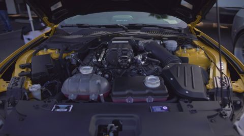 1995 Ford Taurus - The engine bay of a yellow car is open, revealing its supercharged engine and various components.