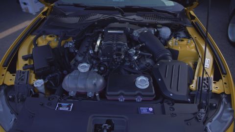 1995 Ford Taurus - The engine bay of a yellow car, showing a supercharged V8 engine and various fluid reservoirs.