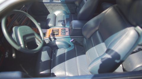 1995 Ford Taurus - The interior of a car shows plush leather seats and a wood-grain accented center console.