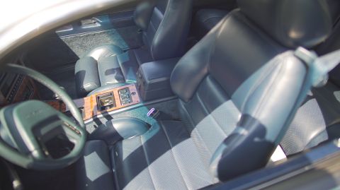 1995 Ford Taurus - The interior of a 1995 Ford Taurus shows dark blue leather seats and wood trim accents.