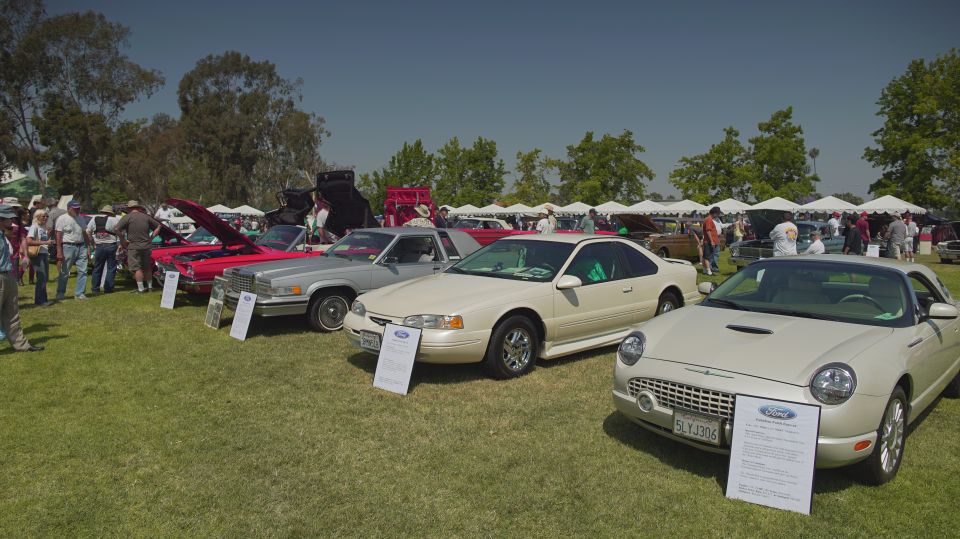 Several cars parked on grass at an outdoor car show, with people milling around