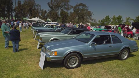 1995 Ford Taurus - A line of classic cars are displayed on a sunny day at an outdoor event.