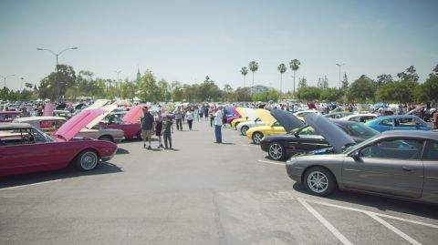 1995 Ford Taurus - A sunny day at a car show with many vehicles on display and attendees milling about.