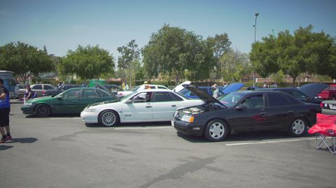 1995 Ford Taurus - A gathering of sedans, including a black 1995 Ford Taurus, parked in a lot on a sunny day.