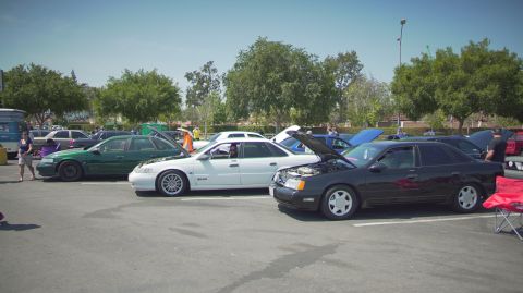 1995 Ford Taurus - Multiple sedans are displayed at an outdoor event, with several owners showing off their engines.