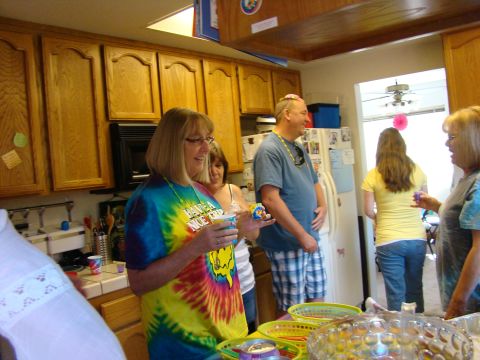 1989 Ford Bronco - A group of people are gathered in a kitchen, with one woman in a colorful tie-dye shirt holding a cup.