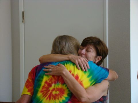 1989 Ford Bronco - A warm embrace between two women, one in a colorful tie-dye shirt, in front of a closed door.