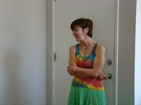 1989 Ford Bronco - A woman wearing a colorful tie-dye tank top and a long green skirt stands with her arms crossed in front of a closed door.