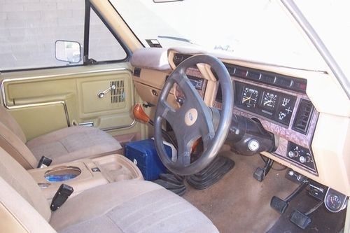 Interior of a 1985 Ford Bronco showing dashboard, steering wheel, and tan seats
