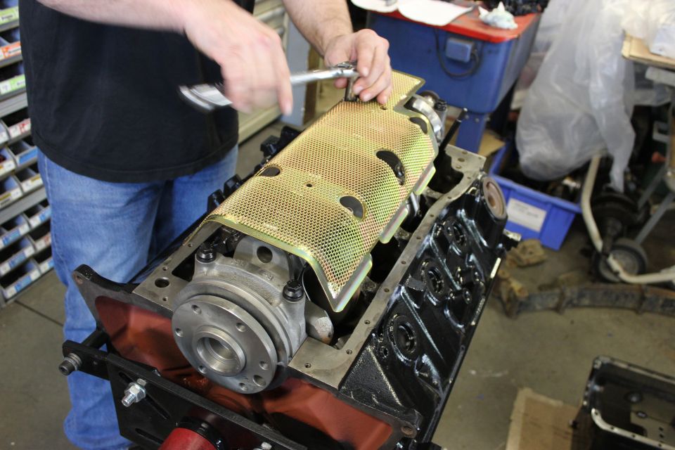 Engine block assembly with a yellow perforated cover being installed