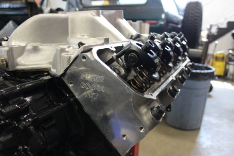 1979 Ford Bronco - A V8 engine with a "Super Cobra Jet" valve cover is shown in a workshop setting.