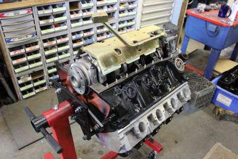 1979 Ford Bronco - Engine block assembly on a stand in a workshop with parts bins in the background.