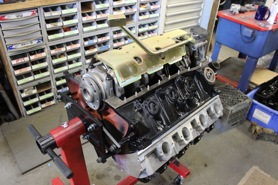 Engine block on a red stand, with oil pan removed and crankshaft visible