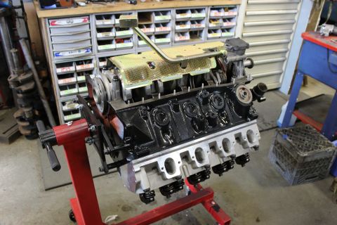 1979 Ford Bronco - Engine assembly on a stand in a workshop environment, with storage cabinets in the background.