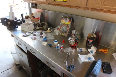 1979 Ford Bronco - Various automotive parts and tools are laid out on a metal workbench.