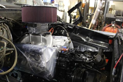 1979 Ford Bronco - The engine bay of a vehicle is partially assembled, with a large air filter and intake manifold prominently displayed.