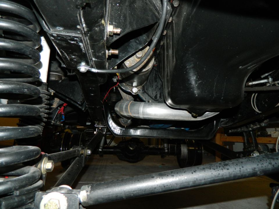Underside view of vehicle suspension, exhaust pipe, and differential. Supermotors.net logo visible