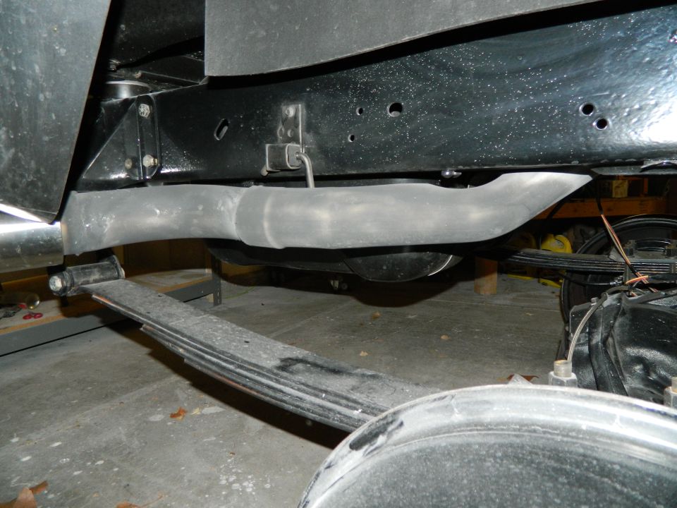 Underside of a vehicle showing an exhaust pipe, leaf spring, and differential