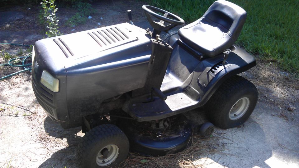 Riding lawn mower parked outside on concrete and dirt