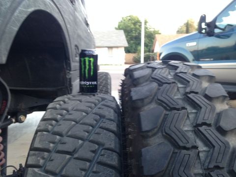 1987 Suzuki Samurai - Monster Energy can used to show scale next to a large off-road tire. Another vehicle is visible.