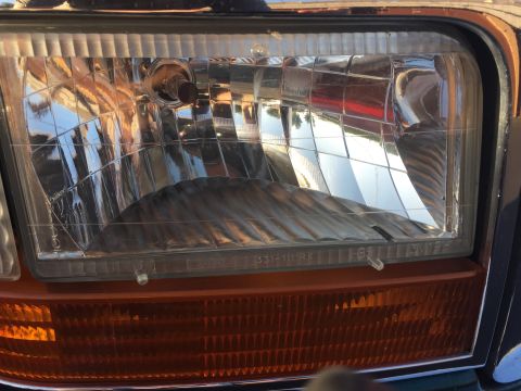 1996 Ford Bronco - Close-up of a 1992 Ford Bronco's headlight and turn signal assembly, revealing the textured amber lens and clear fluted headlight cover.