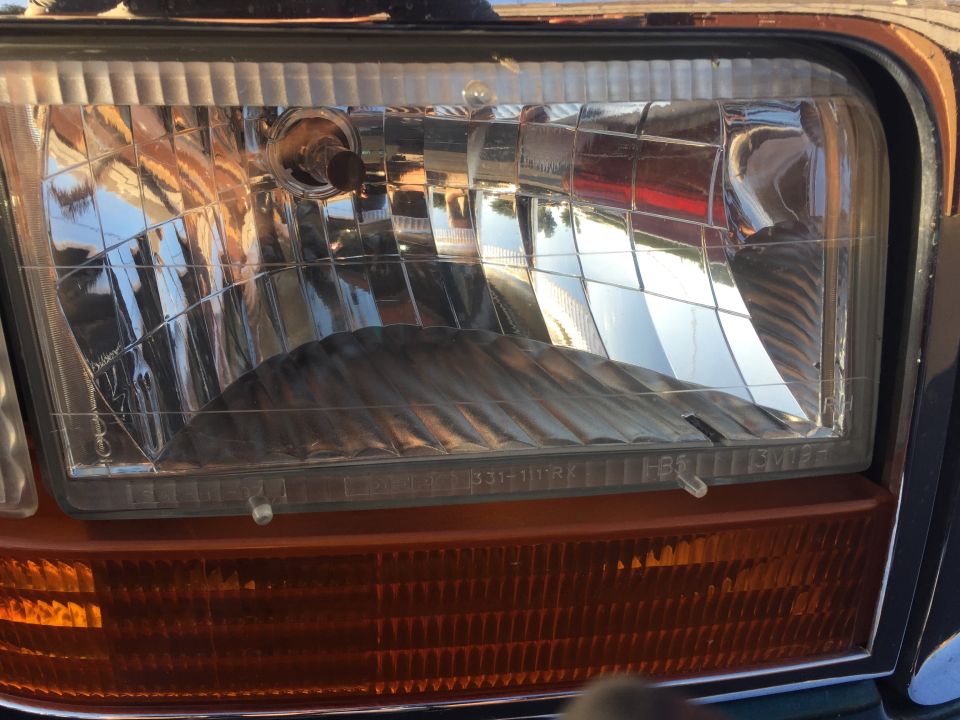 Headlight and amber turn signal assembly on a 1992 Ford Bronco, showing a clear lens with internal fluting and a textured amber lower section