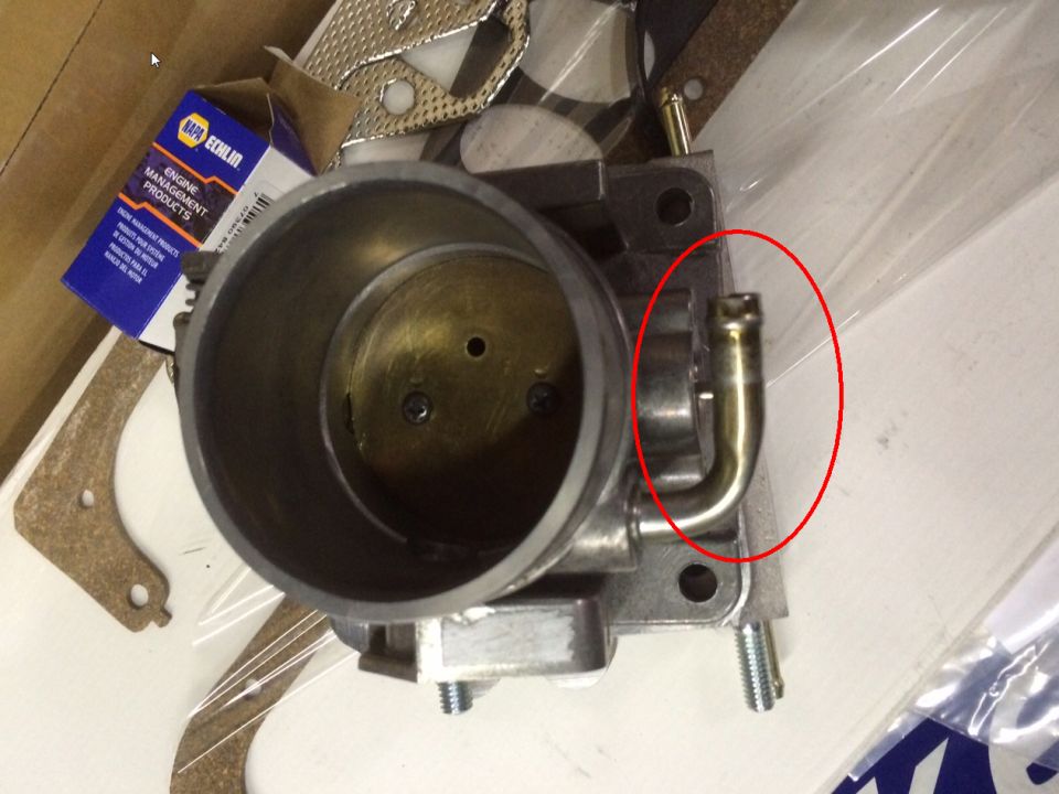 Throttle body with a brass vacuum hose fitting circled in red. NAPA Echlin box in background