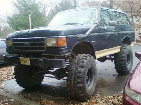 1990 Ford Bronco - This modified Ford Bronco features a snorkel and oversized tires, suggesting it's built for off-road use.