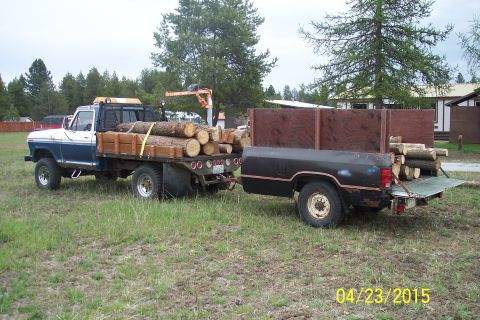 1973 Ford F-250 - A flatbed truck and trailer are loaded with logs, ready for transport.