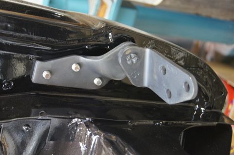1979 Ford Bronco - Close-up of a vehicle's hood hinge, showing a stamped 'S' on the metal bracket.
